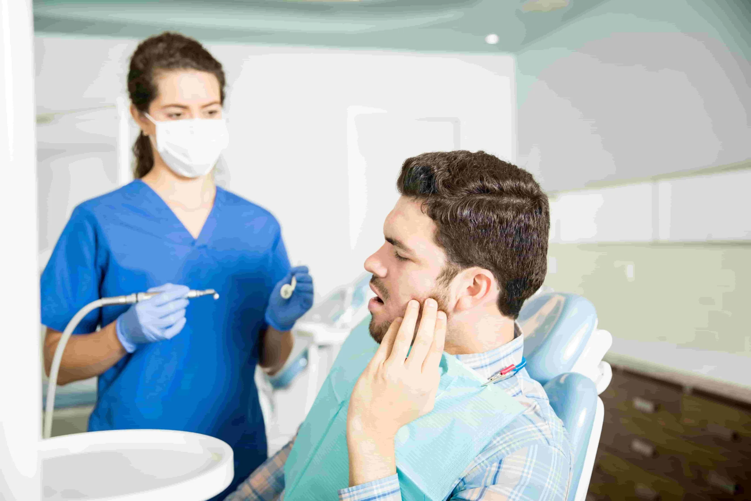 mid adult man suffering from toothache while looking dentist with tool clinic scaled